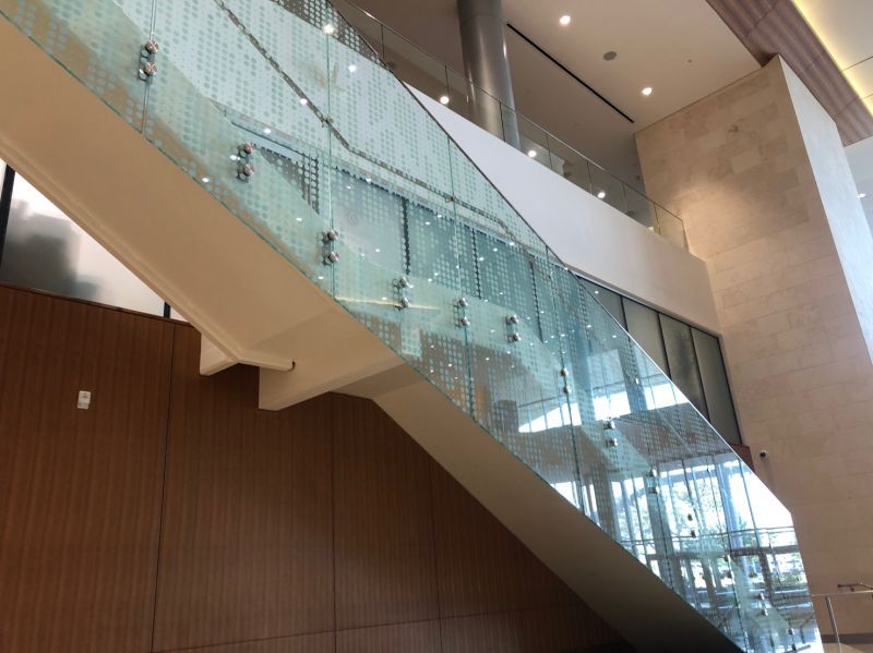 From this close-up view you can see that the attachment points where the glass is secured to the staircase are not consistent from pane to pane (they start near the midpoint of the pane at the bottom and move toward the bottom of the pane as you move up).
